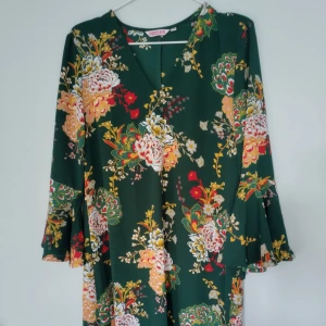 Grön tunika trumpetärm - Grön, blommig tunika med trumpetärm från Indiska Storlek S