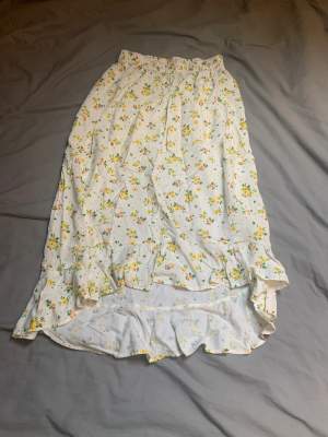En blommig fin kjol, den är längre bak med volanger och kortare fram till.