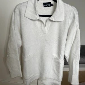 Stickad tröja  - Vit stickad tröja med två fickor. Lite oversize i modellen. En lite fläck längst ner.
