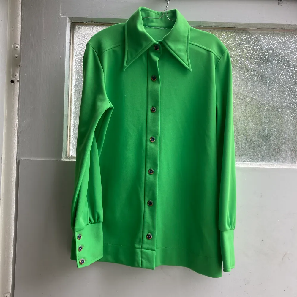 Unik grön Vintage skjorta/blus från 60-70-tal. Otroligt fräsch och ett mycket mjuk material men inga lappar kvar kring detta. Vackra pärlemoknappar även på macheterna. Snyggt sytt ok i ryggen. . Blusar.