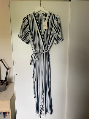 Randig jumpsuit - Vit/blå randig jumpsuit från BikBok, storlek M. Inte använd, prislapp kvar på den