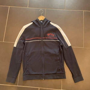 Hugo boss zip hoodie herr - Hej, säljer min Hugo boss zip hoodie då den blivit lite liten för mig. Den är i storlek S (herrstorlek) och jag köpte den för 2000kr på Hugo boss hemsida för ungefär 2,5 år sedan och det finns inget fel på den. Kom gärna priv för fler bilder!!