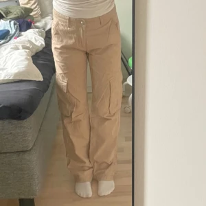 Lågmidjade cargobyxor - Beige Lågmidjade cargobyxor ifrån Gina tricot som är väl omhändertagna. Säljer för att de inte kommer till användning. Precis som nyskick. Nypris 500