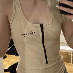 Beige body med text och zip, oanvänd i nyskick och passar storlek XS,S,M