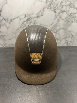 Samshield hjälm - Säljer min samshield hjälm då jag slutat tävla. Storlek 58 aldrig ramlat i backen med då jag haft den som tävlingshjäm. Nypris när jag köpte den var 5.500kr. Den är brun i mocka med gulddetaljer. Kom med prisförslag!