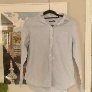 Ljusblå skjorta - Ljusblå skjorta från gina tricot. Oanvänd. Färgen syns lite dåligt på bilden men klassisk ljusblå som det brukar va på skjortor.