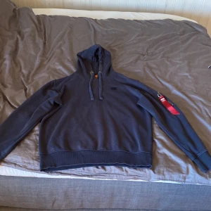 Alpha hoddie  - Mörkblå hoddie, lite urtvättad och några små fläckar men inte direkt ngt man tänker på, går möjligtvis bort med rätt medel! Storlek M
