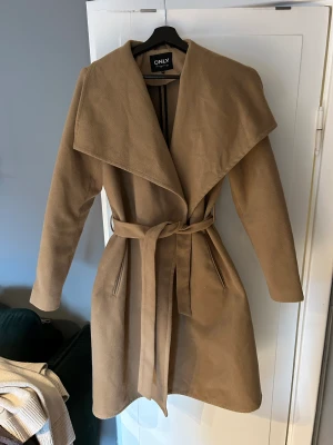 Beige Camel Kappa  - Fin kappa i bra skick från Only. storlek M, passar någon som är S. Kappan är använd fåtal gånger och i en Camel beige färg. Nypris 799 