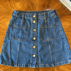 Jeanskjol - Blå jeanskjol med bruna detaljtrådar i 100% bomull från H&M divided - bra skick och knappt använd!