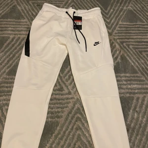 Nike tech fleece byxor - Hej jag säljer 2st Nike tech byxor pågrund utav storleksskäl. Dom är i nytt skick 10/10. De vita  är L men passar M också. De röda är xl men passar både L och M de är thighta i storlekarna. Ta båda för 700kr eller 300 kr st 
