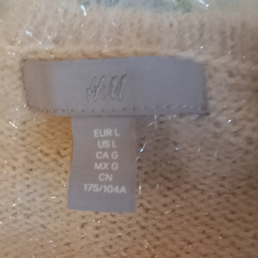 Stickad tröja från H&M. Aldrig använd. Den har en slits på båda sidor och är ljusgul/beige i färgen. Nypris är 400kr.. Stickat.