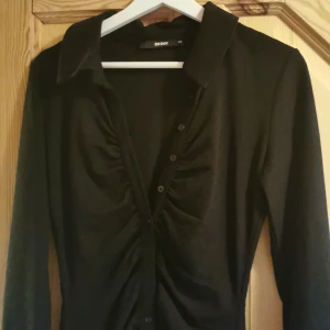 Svart klänning - Klänning från bikbok. I nyskick. Storlek XS med passar även S. Knappar hela vägen och rysch vid bysten. Mycket fin! 
