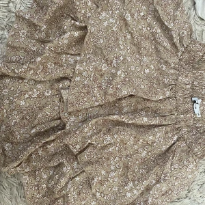 Brun volangkjol - Kort brun volangkjol med vita blommor.