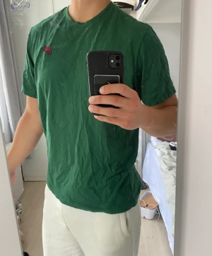 Grön Nike T-Shirt - Helt ny grön T-shirt från Nike med en röd logga vid bröstet. Storlek L