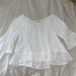 Vit blus - Vit blus med trekvarts ärmar och volang. Den är i storlek 140 men passar som xxs, säkert oxå på xs men den är ganska kort. Den är endast använda 1-2 gånger. 