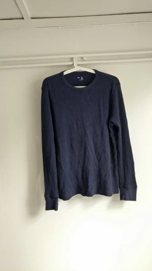 Marinblå tunn långärmad tröja - Tunn långärmad som funkar med eller utan tisha under. Mjukt å skönt bomullsmaterial med randig/våffel textur. Köparen står för frakt