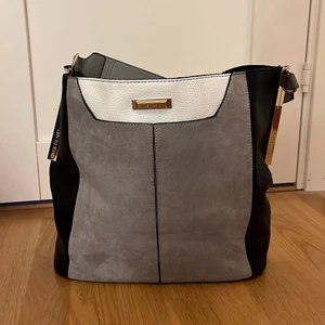 Grå, svart, vit väska - Jättesnygg väska som funkar i alla lägen! Finns även ett långt grått band om man skulle vilja ha det! Orginalpris: 600kr ❤️ Funkar som skolväska med dator osv i ❤️