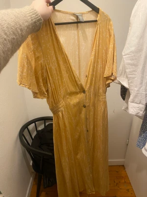 Gul blommmig klänning - Så fin gul klänning, går också att ha öppen som en ”släng över”. Säljer pga inte min stil längre