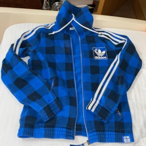 Adidas kofta utan luva - En jättefin äkta adidas kofta som är i färgen blå, vit och svart. Är i storlek S/36. Det har gått bort lite vid adidas loggan men det är inget man tänker på. Köparen står för frakten ❤️