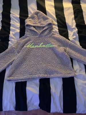 En hoodi.  - Den är super mysig. Den har en neon grön/gul text inmitten. Den är tvärgatad.