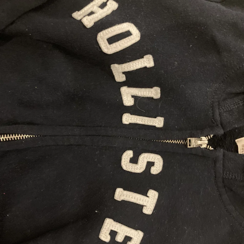 En hollister mörkblå zip upp hoodie med vita bokstäver. Har själv använt hoodien 2-3 gånger men köpt köpt secondhand. Används tyvärr inte då den är förlusten för mig:( Om du har funderingar eller frågor skriv gärna!!!!!. Hoodies.