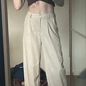 Byxor från NAKD - Beige byxor med tunna svarta ränder. Fin passform och fint fall i byxorna. 