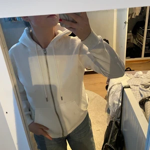Vit zip hoodie - Säljer en vit zip hoodie från hm, i storlek M. Köpt för två somrar sen. Den har en fläck på en av fickorna där fram men det är inget man tänker på så mycket, men säljer endå billigt för det. Använd nån gång för länge sen! Skirv privat för frågor/bilder. 