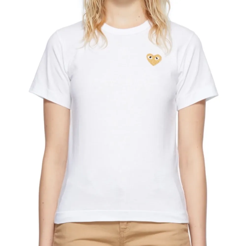 Säljer en klassisk vit t-shirt från Comme des garcons med ett guldigt hjärta 💛 I fint skick!. T-shirts.