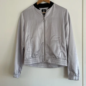 Tunn silverfärgad jacka i bomber-stil  - Storlek 10/38/M, oanvänd (har bara hängt i garderoben), mycket gott skick. 