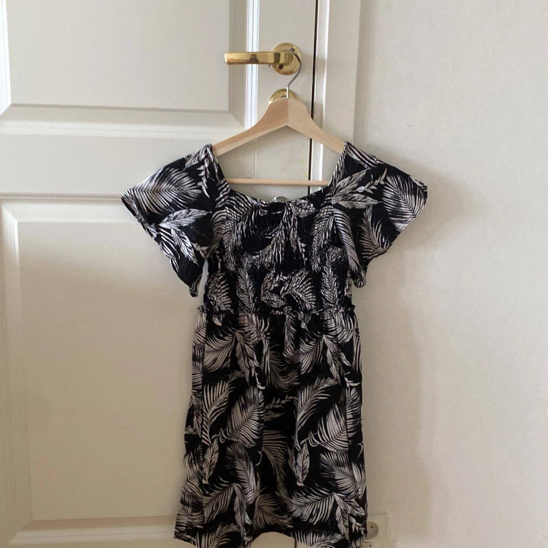 Svart klänning med vita fjädrar i st 140