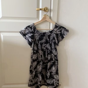 Svart klänning med vita fjädrar i st 140 - Svart klänning med vita fjädrar aldrig använd