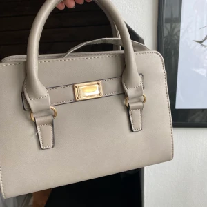 Väska - Grå väska med gulddetaljer, med både långa och korta band:)