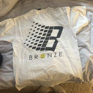 Fin Bronze T-shirt med tryck på ryggen (första bild), använt rätt mycket och har ett minimalt hål på axeln 