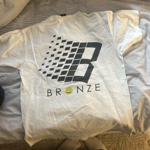Bronze Tisha - Fin Bronze T-shirt med tryck på ryggen (första bild), använt rätt mycket och har ett minimalt hål på axeln 