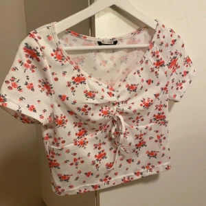 Vit topp med små rosa blommor - Supergullig topp med ett mönster med små rosa blommor och snörning. Aldrig använd!