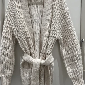 Stickad kofta - Stickad kofta med knyt i midjan. Fint skick men någon liten tråd som låstnat på några ställen. 