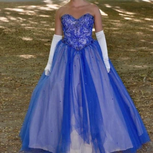 Balklänning  - Säljer min fina balklänning, endast använd 1 gång och köptes 2021, bra skick men däremot har lite av de blåa tyget gått sönder längst ner på baksidan av klänningen då någon trampa på det. Men det är inget som syns och går enkelt att fixa. Köptes för 11000