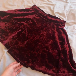 Lila kjol i sammet! - Säljer denna fantastiska kjol i glansigt sammetstyg då den inte passar mig. Den har ett stretchigt band i midjan och sitter löst. På bilden ser den lite röd ut men den är i en vacker mörklila färg. 