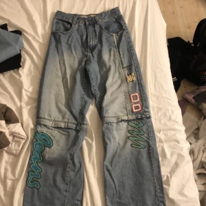 Jeans  - Blå jeans men en massa text på runt byxorna 