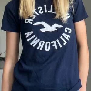 Marinblå t-shirt med tryck från Hollister i strl xs. Passar i storleken och superskön i  materialet. Köparen står för frakt!