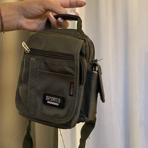 Väska  - En liten väska som har jättemkt fack! Dragkedjan på bild 2 är trasig, men märks ej när flärpen är över. 