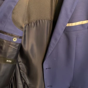 Ny ull kostym i fin ull från Boss - Enkelknäppt ullkostym från Boss. Kostymen är tillverkad i en fin kvalitet av nyull, vilket ger en klassisk och dressad look. Anvendt två gånger. 