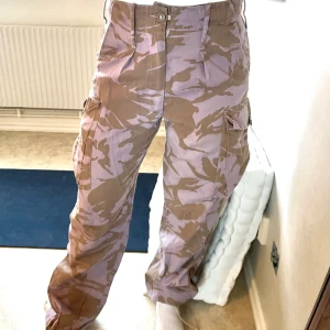 Militär cargobyxor  - Rosa/bruna coola cargobyxor i militär. Från Urban outfitters tror jag. Går att snöra åt nedtill för att ändra utseendet runt vristen. Väldigt sköna att ha på sig!  Mått enligt lapp på byxan Midja: 80cm Ben: 72cm