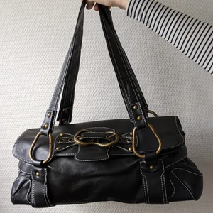 y2k axelväska  - svart y2k axelväska i läder med vita sömmar och stora gulddetaljer <3 har använt en hel del, därav vissa defekter :) MÅTT: 35x12 cm höjd 15 cm fråga bara om ni vill se en specifik del elr så (köparen betalar frakt!!)