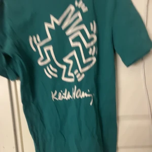 T-shirt med ryggtryck - Jättecool t-shirt som bara inte kommer till användning. Färgen är grön blå men mer åt det gröna hållet, inte exakt som på bilden. Skriv för föer bilder eller om du har frågor. 