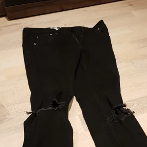Jeans  - Ett par svarta jeans med hål i knäna, knappast användt