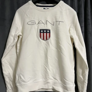 Gant sweatshirt - Vit Gant tjocktröja med stort tryck. Använd fåtal gånger, tröjan är i fint och bra skick. Storlek XS. Pris kan diskuteras. Köparen står för frakten. Betalning sker via Swish.