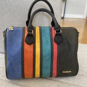 Unik väska  - Superfin unik väska som inte längre kommer till användning. Märket är Desigual och är köpt i mall of dubai. Finns även tillhörande axelband som kan skickas med. Knappt använd!  Längd:30cm Bredd: 20cm Höjd:23cm
