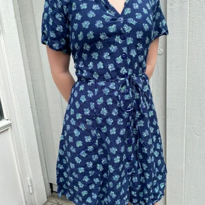 Klänning Strl S - Klänning köpt på second hand. Mörkblå med gröna/lila blommor. Storlek Small.