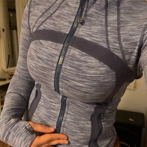 Lululemon Träningsjacka - Knappt använd träningsjacka från Lululemon, som ny. Tajt passform, storlek 8 motsvarande typ S. Jag är typ storlek 38, så det skulle sitta lösare på någon som är XS. Sitter fint på alla kroppsformer, jättefin lila färg. Har hål för tummarna, samt så kan man vika ner armarna för att täcka händerna. Andningsbar material